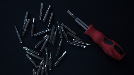 A small screwdriver with an additional set of nozzles on a black background.