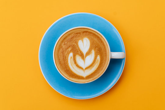 Cup of fresh coffee on blue background, top view