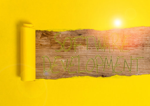 Conceptual hand writing showing Software Development. Concept meaning software is created using a specific programming Cardboard which is torn placed above a wooden classic table