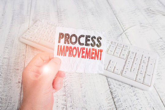 Writing note showing Process Improvement. Business concept for ongoing effort to improve products services or processes Man holding colorful reminder square shaped paper wood floor