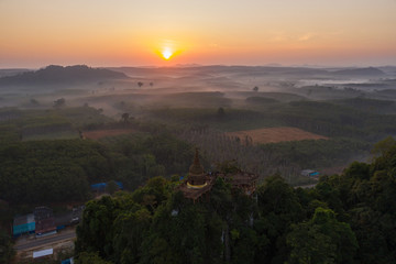 Fototapeta na wymiar Beautiful sunrise with pagoda on the top of rock and tree with fog at Khao Na Nai Luang Dharma Park,Surat thani province,Thailand