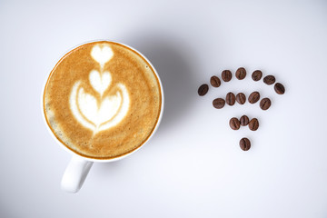 Cup of coffee and coffee beans forms a wifi symbol on white from top landscape format