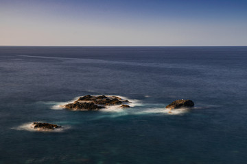 Volcanic rocks in Atlantic ocean, long exposure photography, horizon with sunset light, San Juan de la Rambla coastline, Tenerife, Canary islands, Spain