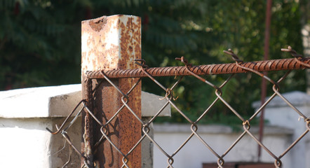  The end of the fence, made of metal netting. Support post made of old rusty metal.