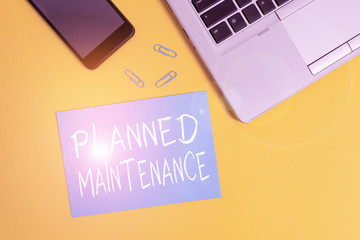 Text sign showing Planned Maintenance. Business photo showcasing reventive maintenance carried out base on a fixed plan Trendy open laptop smartphone small paper sheet clips colored background