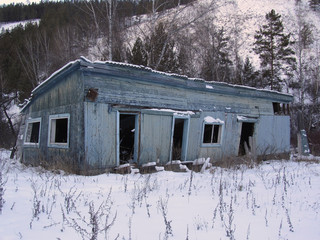 Abandoned wooden house. In the winter in the mountains. Old ruined house. The dilapidated desolate village building. Decrepit wooden structure.