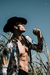 Portrait of a handsome young man in a black hat. Fashion country concept. Outdoor shot.