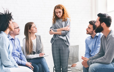 Addicted woman talking talking during rehab group meeting