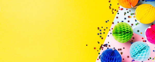 Festive yellow background with colorful paper balls. Greeting card concept voor birthday, party, invitation, carnival. Copy space, top view, flat lay. Banner.