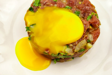 Beef Tartare cold appetizer of raw minced meat with egg yolk, spices, onions, olive oil, lemon juice