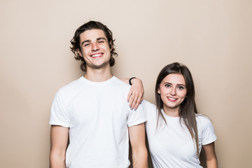 Portrait of a smiling young couple hugging standing together over beige background