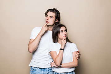 Naklejka premium Young couple holding chins and being concentrated on their problems isolated on beige background