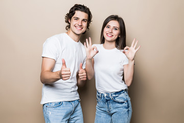Portrait of beautiful people man and woman in basic clothing posing together at camera with thumbs...