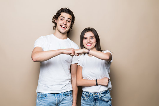Young couple give five on beige background