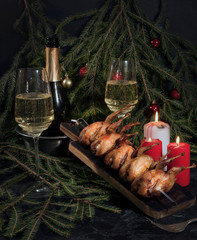 grilled stuffed quail on a spit and champagne for Christmas dinner. Christmas dinner by candlelight at home.