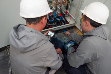 Electricians take measurements. Worker in uniform.