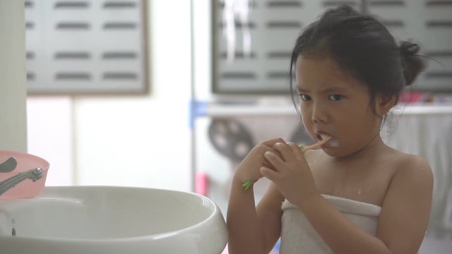 Asian child cute or kid girl brush teeth by toothbrush with toothpaste and themselves for clean and learning in basin to prevent tooth decay and fluoride coating with white teeth for dental and smile