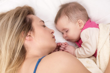 Obraz na płótnie Canvas Mom and baby girl sleeping in bed