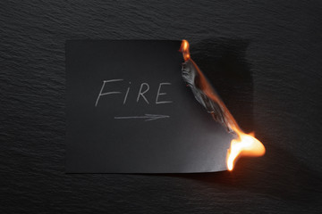 Burning piece of black paper with the word 