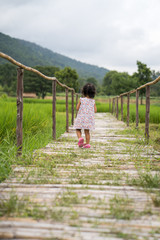little girl walking on walkway through the paddy rice field.