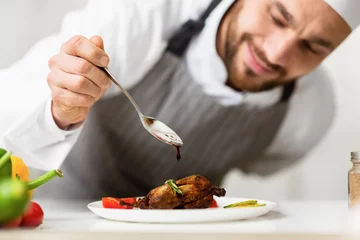 Fotobehang Cook Man Pouring Sauce On Chicken Plating Dish In Kitchen © Prostock-studio