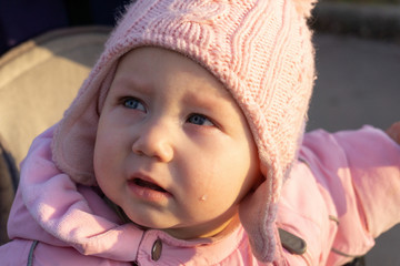 A little girl with tears crying in a pram.