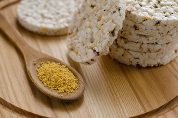 Soy lecithin in a wooden spoon on a wooden backgroundand round multigrain rice cakes.