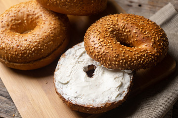 Sesame bagels with spreadable cream cheese on wooden background