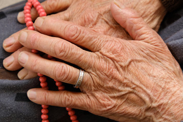 Fototapeta premium old woman with ring on her finger worships her hand with rosary,