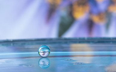 water drop splashing in a lake and reflecting a flower on the background