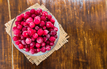  Frozen cranberries in a plate on a dark wooden background. Flat lay. Copy space.