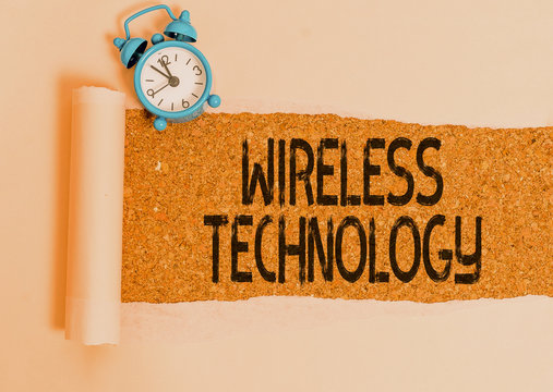 Writing note showing Wireless Technology. Business concept for a technology that allows wireless communication Alarm clock and torn cardboard on a wooden classic table backdrop