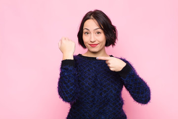 young pretty woman looking impatient and angry, pointing at watch, asking for punctuality, wants to...