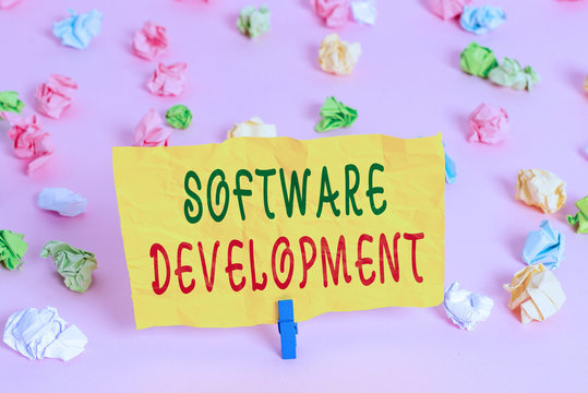 Handwriting text writing Software Development. Conceptual photo software is created using a specific programming Colored crumpled papers empty reminder pink floor background clothespin