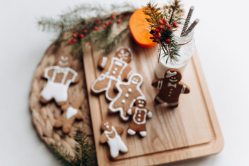 painted gingerbread man Christmas gingerbread cookies lie on a wooden board.