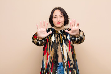 young pretty woman smiling and looking friendly, showing number nine or ninth with hand forward,...
