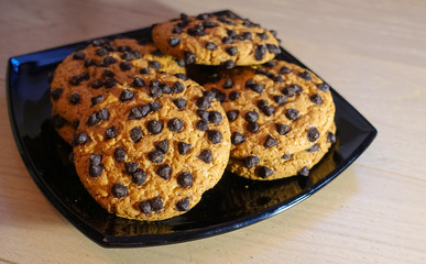 Oatmeal cookies with chocolate chips on a black plate
