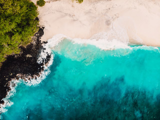 Tropical white sand beach and volcanic rocks with turquoise sea. Aerial view