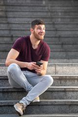 young man sitting on steps outside with cellphone