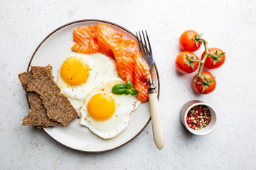 Top view of healthy breakfast with fried eggs and smoked salmon in a plate