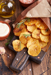 Fototapeta premium Crispy potato chips. Slices of potato, roasted with sea salt and rosemary. Delicious snack served with sauce. Fast food.