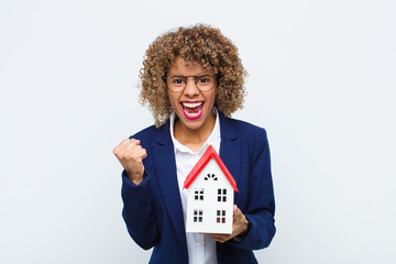 young african american woman shouting aggressively with an angry expression or with fists clenched...