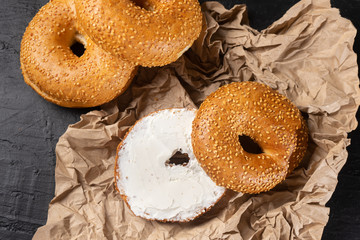Sesame bagels with spreadable cream cheese on dark background