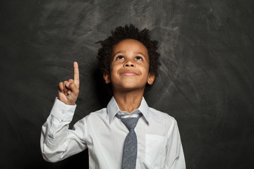 Kid little boy pointing up on black background