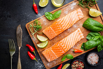 Raw salmon fillet and ingredients for cooking, seasonings and herbs on a dark background . Top view