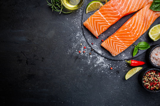 Raw salmon fillet and ingredients for cooking, seasonings and herbs on a dark background . Top view