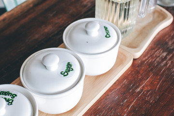 Ingredients sugar and cream white ceramic cup for coffee coffee with cream and tea spoon on saucer,...