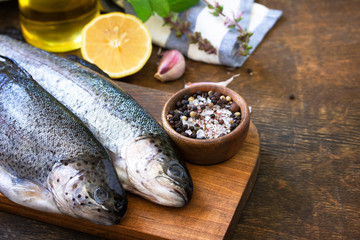 Fresh raw trout fish and pickle ingredients on a wooden table. Cooking grilled fish preparation. Copy space.