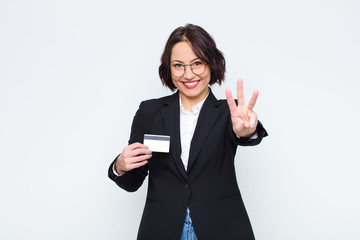 young pretty woman smiling and looking friendly, showing number three or third with hand forward,...