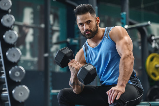 Handsome Bodybuilder Picking Up Dumbbells At Gym